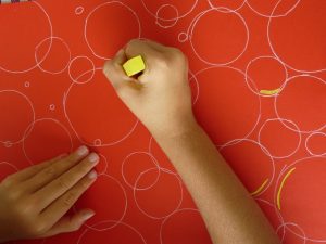 cercles blancs fond rouge enfant main pastel